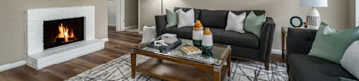 Spacious living room with wood burning fireplace and grey painted walls at Woodlake on the Bayou Apartments in Houston.