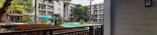 Luxury apartments with spacious balconies, resort-style pool with fountains, pool-side lounge chairs, spa, and palm trees at The Voss Apartments in Houston.