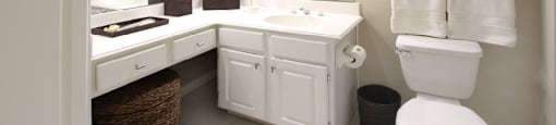 Luxury apartments with white cabinets, linen closet, extra cabinet space, cultured marble vanity, built-in vanity, and porcelain tiled floor at The Biltmore Apartments in Omaha, Nebraska