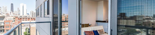 a balcony with a couch and glass doors and a city in the distance