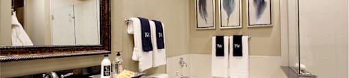Spacious bathroom with oval soaking tub, separate shower with glass enclosure, and granite slab vanity top Tuscany Walk Apartments in Houston.