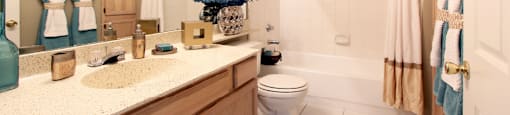 Luxury apartments with spacious bathrooms with tiled floors, extra storage and cabinet space, oval soaking tubs, granite countertops, and washed oak cabinets in north Dallas at Kensington Square Apartments.