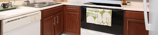 Spacious u-shaped kitchen with lots of cabinet space, lots of counter space, porcelain tile floor, and rich brown toned cabinets at The Biltmore Apartments in Omaha, Nebraska
