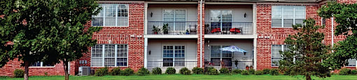 Luxury apartments in central Omaha with golf course views, scenic views, lots of trees, red brick exterior, lush landscaping, beautiful landscaping, and spacious balconies at The Biltmore Apartments