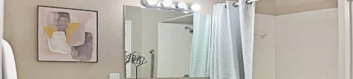 Spacious bathroom with white cabinets, linen closet, extra cabinet space, soaking tub and tiled shower at Breckenridge Apartments in Omaha, Nebraska