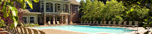 Resort-style pool with large sundeck, poolside lounge chairs, lush landscaping, beautiful landscaping, park-like setting with lots of trees at Breckenridge Apartments in southwest Omaha, Nebraska