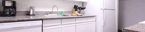 Bright white kitchen with granite countertops and hardwood floors at at Briarwood Apartments in Houston.