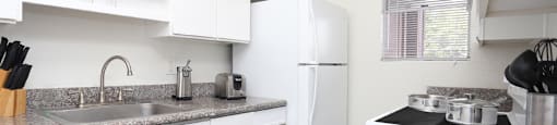 Kitchen with white cabinets, lots of counter space, lots of cabinet space, granite counter tops, and wood plank floors at Briarwood apartments in Houston, Texas