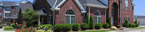 Luxury apartments with red brick exteriors, beautiful landscaping, and scenic views at Rockledge Oaks Apartments in Lincoln, Nebraska