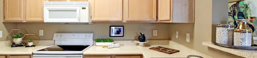 Luxury apartments with spacious kitchen, wood plank floors, breakfast bar, washed oak cabinets, granite countertops, extra pantry storage, and 9-foot ceilings at Kensington Square Apartments.