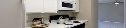 Bright white kitchen with gray wall color, white kitchen cabinets, lots of cabinet space, lots of counter space, spacious dining room and porcelain tile floors at The Inverness Apartments in La Vista, Nebraska