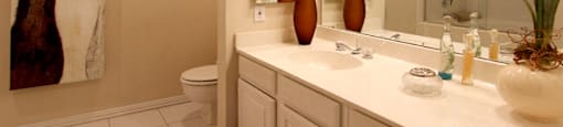 Luxury apartments with spacious bathrooms with tiled floors, extra storage and cabinet space, oval soaking tubs, built-in vanity, glass shower and white cabinets in at The Dorchester Apartments in north Dallas.