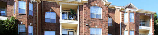 Gated community near the Galleria with brick exteriors, lush landscaping, two swimming pools with poolside lounge chairs, spa, and sauna at The Dorchester Apartments in north Dallas.