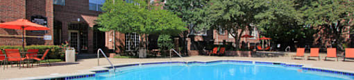 Gated community near the Galleria with brick exteriors, lush landscaping, two swimming pools with poolside lounge chairs, spa, and sauna at The Dorchester Apartments in north Dallas.