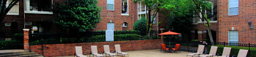 Gated community near the Galleria with brick exteriors, lush landscaping, two swimming pools with poolside lounge chairs, spa, and sauna at The Dorchester Apartments in north Dallas.