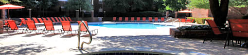 Gated community near the Galleria with brick exteriors, lush landscaping, two swimming pools with poolside lounge chairs, spa, and sauna at The Dorchester Apartments in north Dallas.
