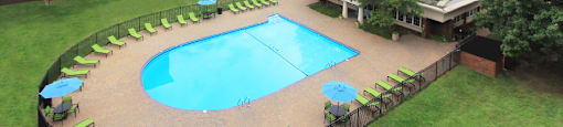 Resort-style saltwater pool with huge sun deck, poolside lounge chairs, and park-like setting with lots of trees and scenic views at Embassy Park Apartments in Omaha, Nebraska