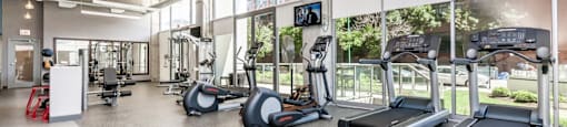 a gym with cardio equipment and windows in a building