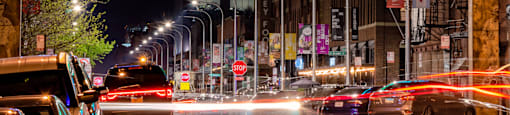 a city street at night with traffic and a neon  Fulton Market District sign