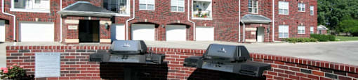 Luxury apartments with red brick exteriors, resident grilling station, and attached garages at Rockledge Oaks Apartments in Lincoln, Nebraska