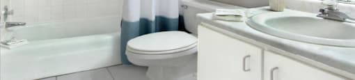 Bathroom with white cabinets, tiled floor and tiled shower with tub at Inwood Apartments in La Vista, Nebraska