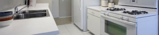 Bright white kitchen with lots of cabinet space and porcelain tile floor at Inwood Apartments in La Vista, Nebraska