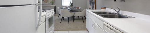 Bright white kitchen with lots of cabinet space, porcelain tile floor, and spacious dining room at Inwood Apartments in La Vista, Nebraska