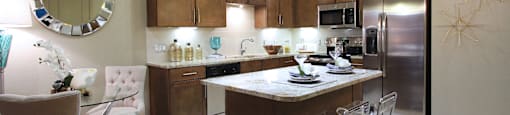 Luxury apartments with spacious kitchen and built-in wine rack, granite countertops, kitchen island, stainless steel appliances, and designer tile backsplash at Tuscany Walk Apartments in Houston Texas.