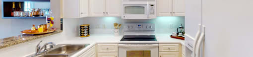 Bright kitchen with granite slab breakfast bar and white cabinets at Tuscany Court Apartments in Houston.