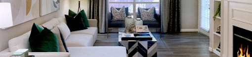 Spacious living room with fireplace, built-in shelves, wood plank floors, large window, and gray colored walls at the Dorchester Apartments in Dallas Texas