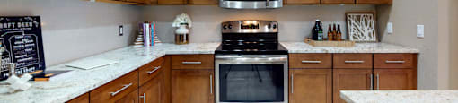 Luxury apartments in Bloomington Minnesota with spacious kitchen, granite countertops, stainless steel appliances, built-in wine rack, kitchen island, and porcelain tile floor at Luxembourg Apartments