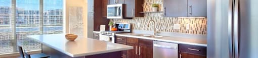A modern kitchen with a wooden floor and stainless steel appliances.