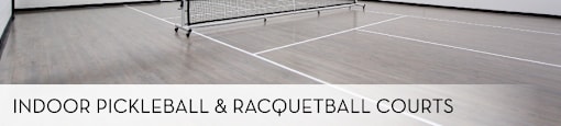 An indoor pickleball and racquetball court with a net and two paddles.