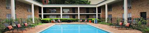 Apartments near the Galleria with multiple swimming pools, sun deck with poolside lounge chairs, brick exteriors and courtyard setting at Plantation apartments in Houston.