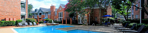 Luxury apartments with two resort-style swimming pools with fountain, poolside lounge chairs, and beautiful landscaping in Dallas.