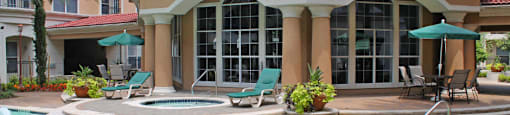 Luxury apartments with resort-style pool with fountains, pool-side lounge chairs, spa, and palm trees at Tuscany Court Apartments in Houston.