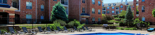 Luxury apartments with red brick exterior, huge swimming pool, poolside lounge chairs, grilling station, and lush landscaping at TurtleCreek apartments in West Des Moines, Iowa
