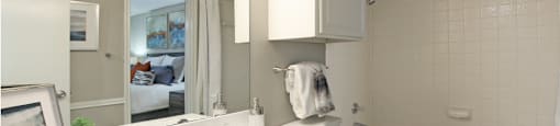 Spacious bathroom with white cabinets and white porcelain tile at Preston Village Apartments in North Dallas