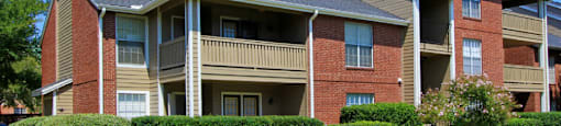 Luxury apartments with red brick exteriors, beautiful landscaping, and spacious balconies at Preston Village Apartments in North Dallas