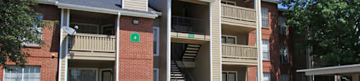 Luxury apartments with red brick exteriors, beautiful landscaping, and spacious balconies at Preston Village Apartments in North Dallas