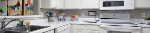 Bright white kitchen with tile floors at Preston Village Apartments in north Dallas