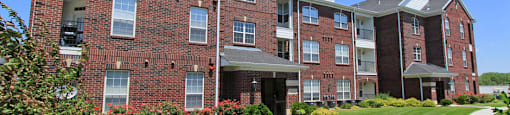 Luxury apartments with red brick exteriors, beautiful landscaping, and scenic views at Rockledge Oaks Apartments in Lincoln, Nebraska