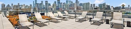 a roof deck with lounge chairs and a view of the city