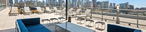 a rooftop patio with blue couches and chairs and a view of the city