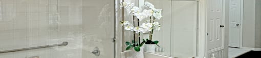 Luxury bathroom with tiled floors, oval soaking tub, built-in vanity, cultured marble vanity, glass shower and white cabinets in at Saddlebrook apartments in Urbandale Iowa