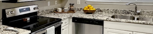 Luxury apartments with granite countertops, white cabinets, stainless steel appliances, and side-by-side refrigerator at Saddlebrook apartments in Urbandale Iowa