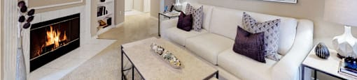Spacious living room with wood-burning fireplace with glass doors, ceiling fan, crown molding, and built-in bookshelves at Tuscany Gate Apartments in Houston.