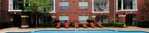 Luxury swimming pool with spacious sundeck, beautiful landscaping, and poolside lounge seating at Tuscany Oaks Apartments in Houston.