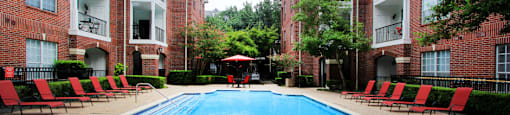 Luxury swimming pool with spacious sundeck, beautiful landscaping, and poolside lounge seating at Tuscany Oaks Apartments in Houston.