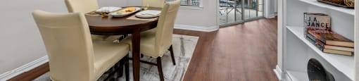 Spacious dining room with built-in bookshelves, hardwood floors, and French doors at Tuscany Villas Apartments in Houston.